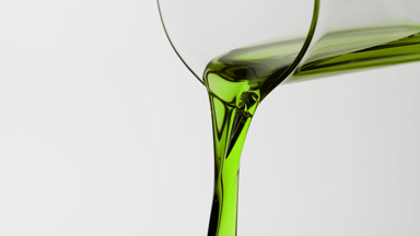 Peppermint oil is being poured from beaker on grey background