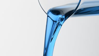 Blue liquid is being poured from beaker on grey background