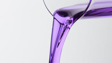 Violet oil is being poured from beaker on grey background