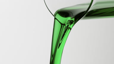 Macro of mint oil is being poured from beaker on grey background