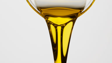 Sesame oil is being poured from beaker on grey background
