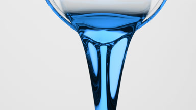 Cyan liquid is being poured from beaker on grey background