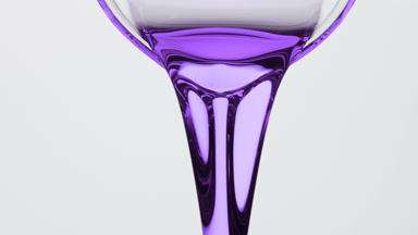 Lavender oil is being poured from beaker on grey background