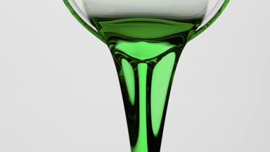 Macro of hemp oil is being poured from beaker on grey background