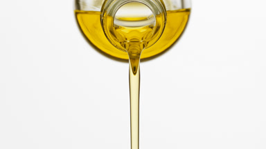 Chamomile oil is being poured from bottle on grey background