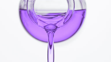 Reagent bottle is being tilted and lavender oil pours from it