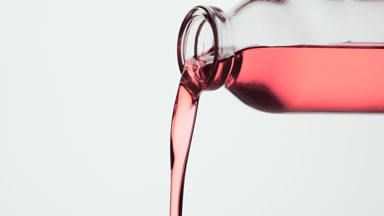 Reagent bottle is being tilted and pink fluid pours from it