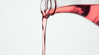 Conical flask is being tilted and rose oil pours from it