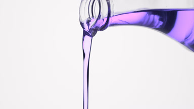 Conical flask is being tilted and violet oil pours from it