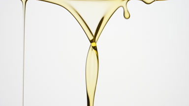Chamomile oil is flowing and dripping down on grey background