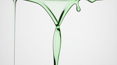 Macro of hemp oil flowing and dripping down on grey background