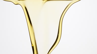Jojoba oil is flowing and dripping down on grey background