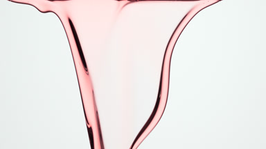 Rosehip oil is flowing and dripping down on grey background
