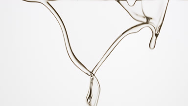 Macro of clear fluid is flowing and dripping on grey background