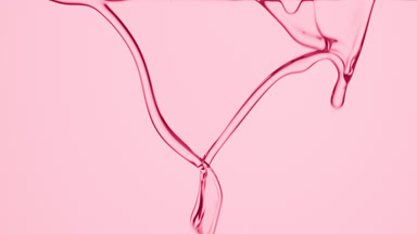 Macro of rose water is flowing and dripping on pink background