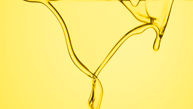 Macro of olive oil is flowing and dripping on yellow background