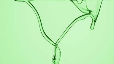 Grapeseed oil is flowing and dripping on green background