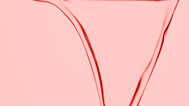 Macro of rose oil is flowing and dripping on pink background