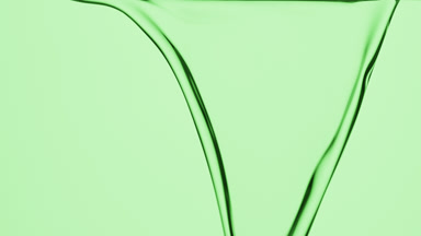 Macro of hemp oil is flowing and dripping on green background