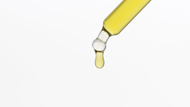 Chamomile extract dripping from lab dropper on grey background