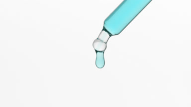 Macro of biotin is dripping from lab dropper on grey background
