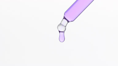 Bakuchoil is dripping from lab dropper on grey background