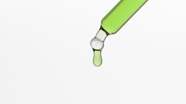 Tea tree extract is dripping from lab dropper on grey background