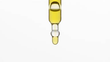 Yellow drops are falling down from dropper on grey background