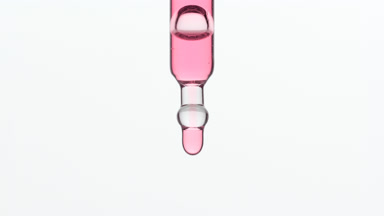 Pink drops are falling down from lab dropper on grey background