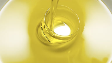 Macro shot of yellow oil is being poured into white ceramic dish