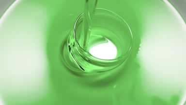 Macro shot of green oil is being poured into white ceramic dish