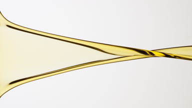 Macro of yellow liquid flowing and dripping on grey background
