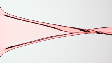 Macro of pink liquid is flowing and dripping on grey background