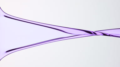 Macro of violet liquid flowing and dripping on grey background