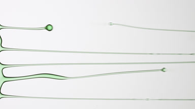 Macro of green fluid is flowing and dripping on grey background