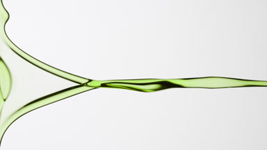 Macro of green tea oil flowing and dripping on grey background