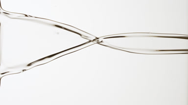 Transparent liquid is flowing and dripping on grey background