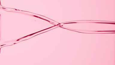 Macro of pink liquid is flowing and dripping on pink background