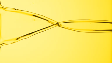 Macro of yellow liquid flowing and dripping on yellow background