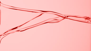 Macro of pink fluid is flowing and dripping on pink background