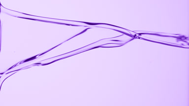 Macro of purple fluid flowing and dripping on purple background