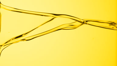 Macro of yellow fluid flowing and dripping on yellow background