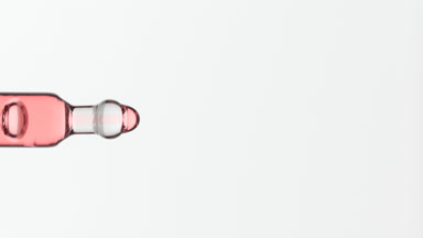 Pink fluid is dripping from lab dropper on grey background