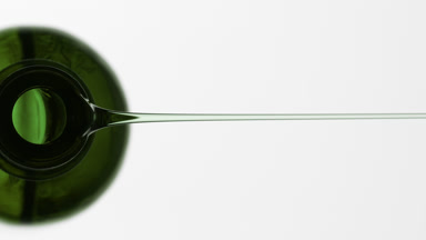Mint oil is being poured from green bottle on grey background