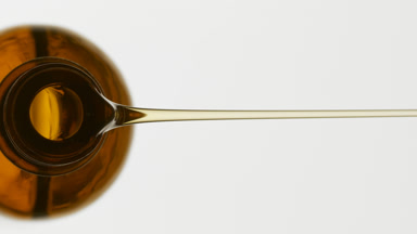 Brown reagent bottle being tilted and yellow oil pours from it