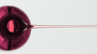 Pink reagent bottle is being tilted and rose oil pours from it