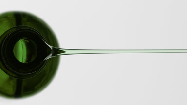 Green reagent bottle is being tilted and green oil pours from it