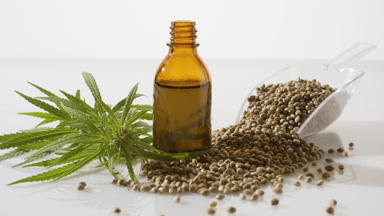 Scoop with hemp seeds, hemp seed oil brown bottle and hemp sprig