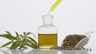 Dropper drips oil in bottle near sprig and scoop with hemp seeds