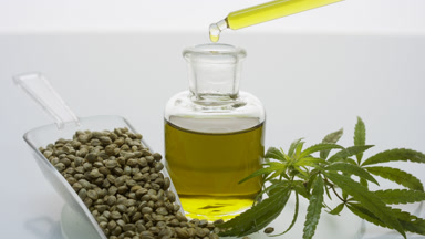 Dropper drips oil in bottle on glass with seeds scoop and sprig